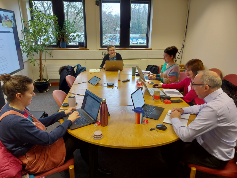 Members of the group working on laptops around a table