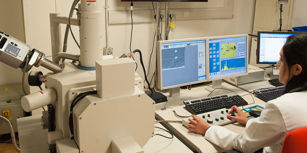 a female researcher works on data at a computer surrounded by technical equipment