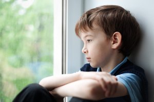 Sad child sitting on window