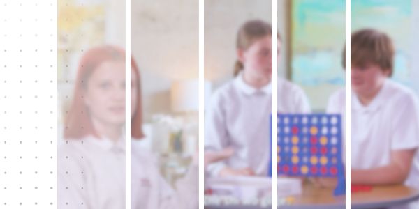 three students playing a board game indoors