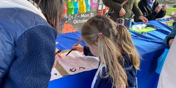 Child writes numbers in Chinese with ink brush at calligraphy stand