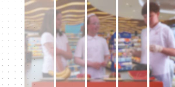 three students in a supermarket trying fruit