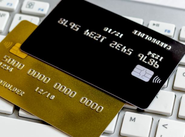 A gold and black bank card resting on a silver computer keyboard with white keys A gold and black bank card resting on a silver computer keyboard with white keys