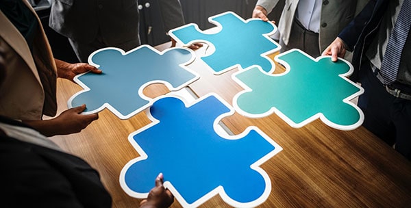 Four persons holding jigsaw puzzle pieces