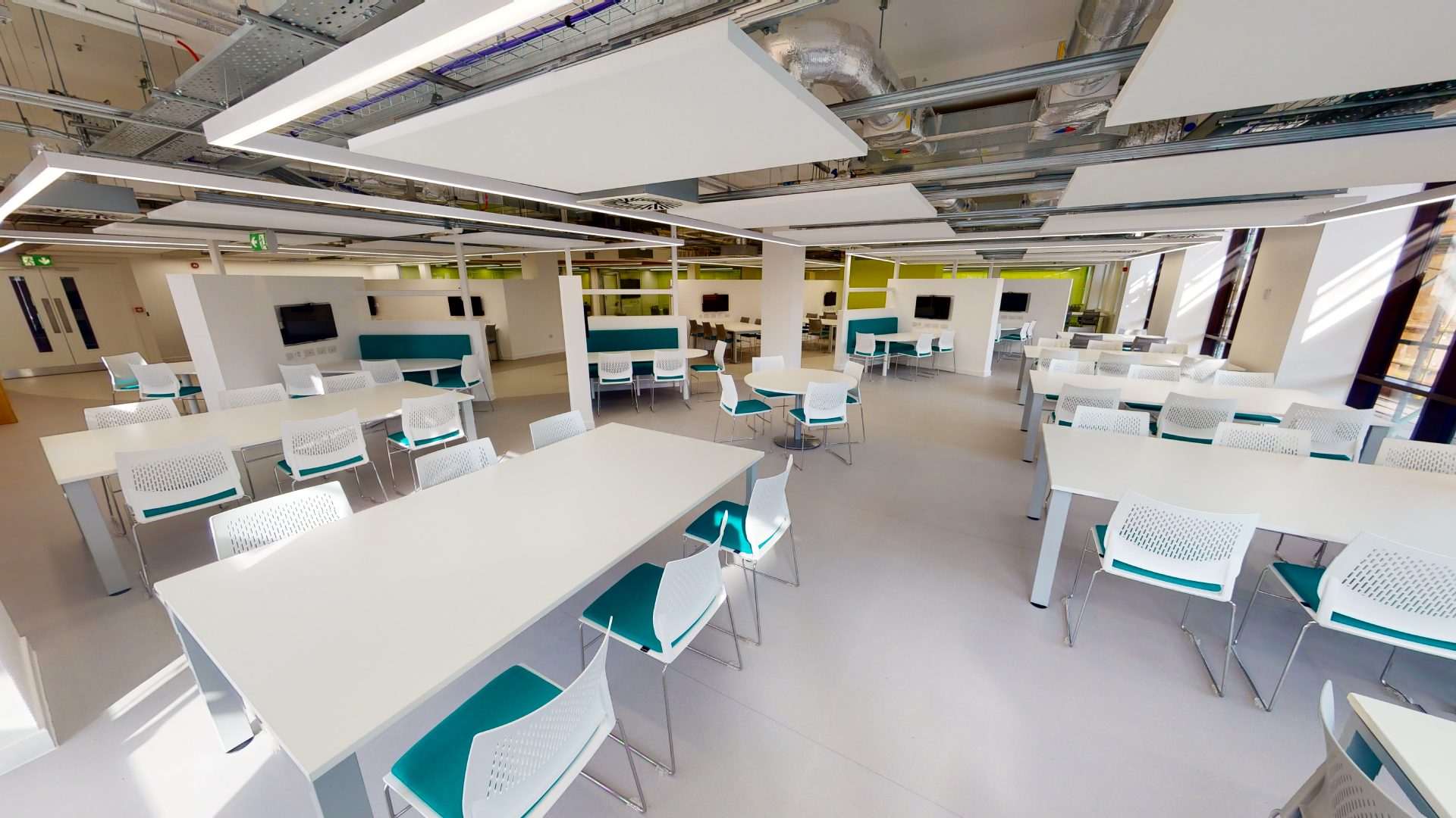 Open study area in the library, multiple big tables with chairs around them.