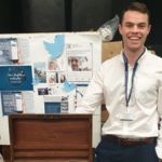 A student at Freshers Fair in front of a board of tweets and Twitter logos