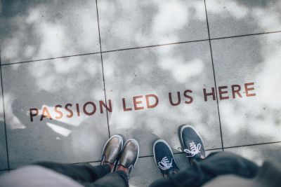 Two pairs of feet stand on a pavement, facing the words 