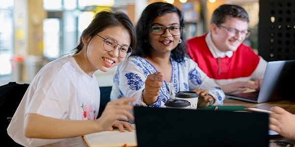Students at a table, watching a laptop