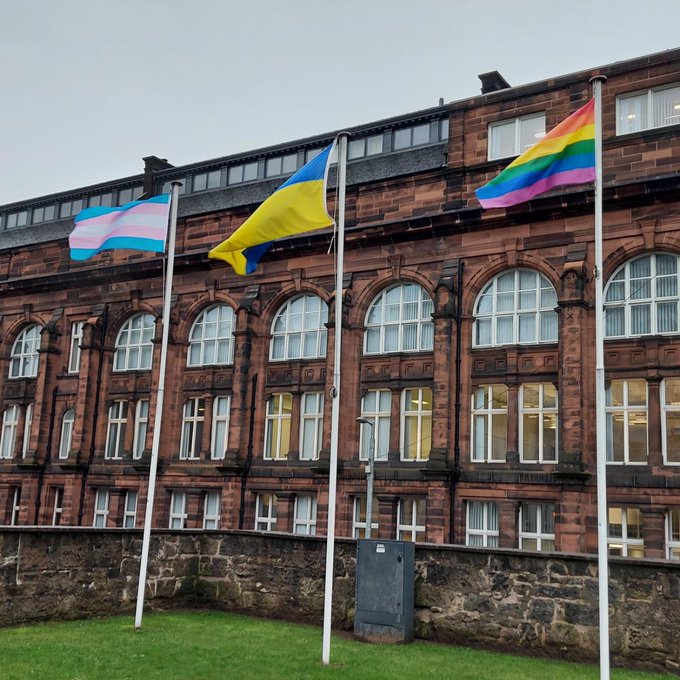 three flag poles on campus with the transgender flag, Ukrainian flag and intersex-inclusive progress pride flag