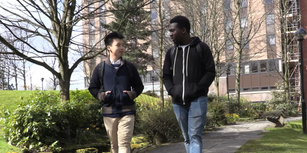 Two students walking near the Student Village