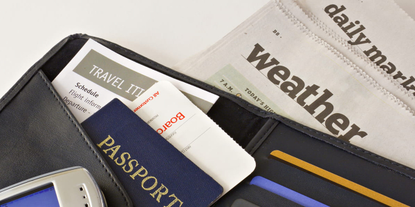 Passport with boarding passes and mobile phone on top of newspapers