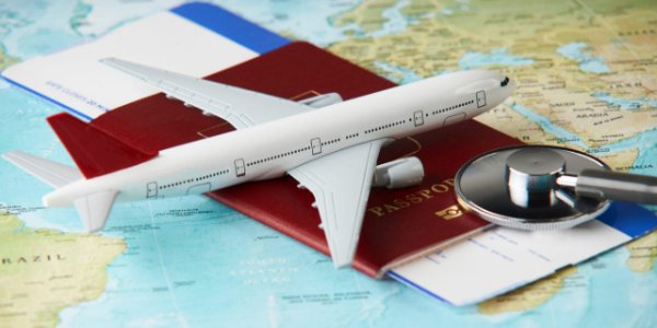 An aeroplane and stethoscope on top of a passport with boarding pass.