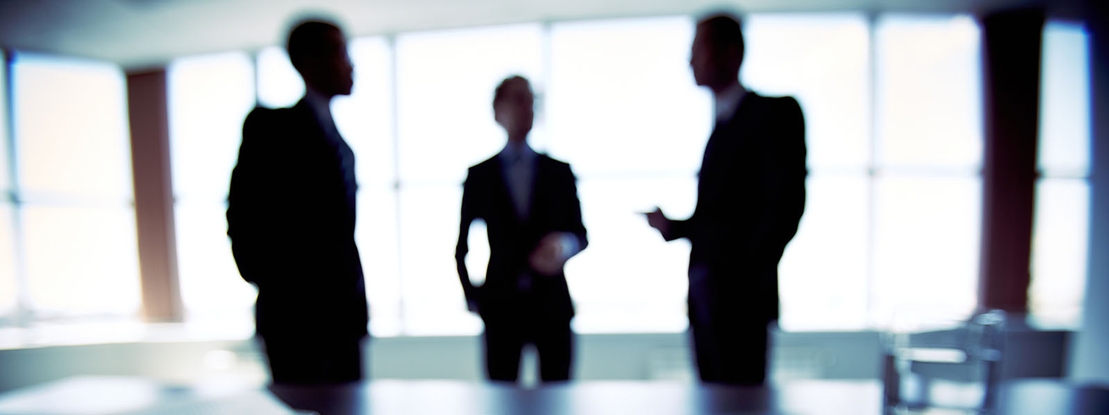 Three silhouettes in a boardroom 
